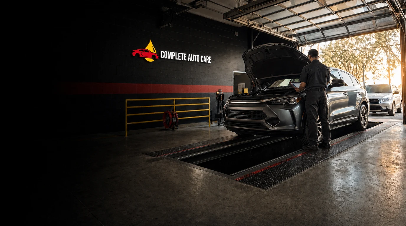 Cinematic Complete Auto Care service bay scene with an open inspection pit and illuminated wall logo